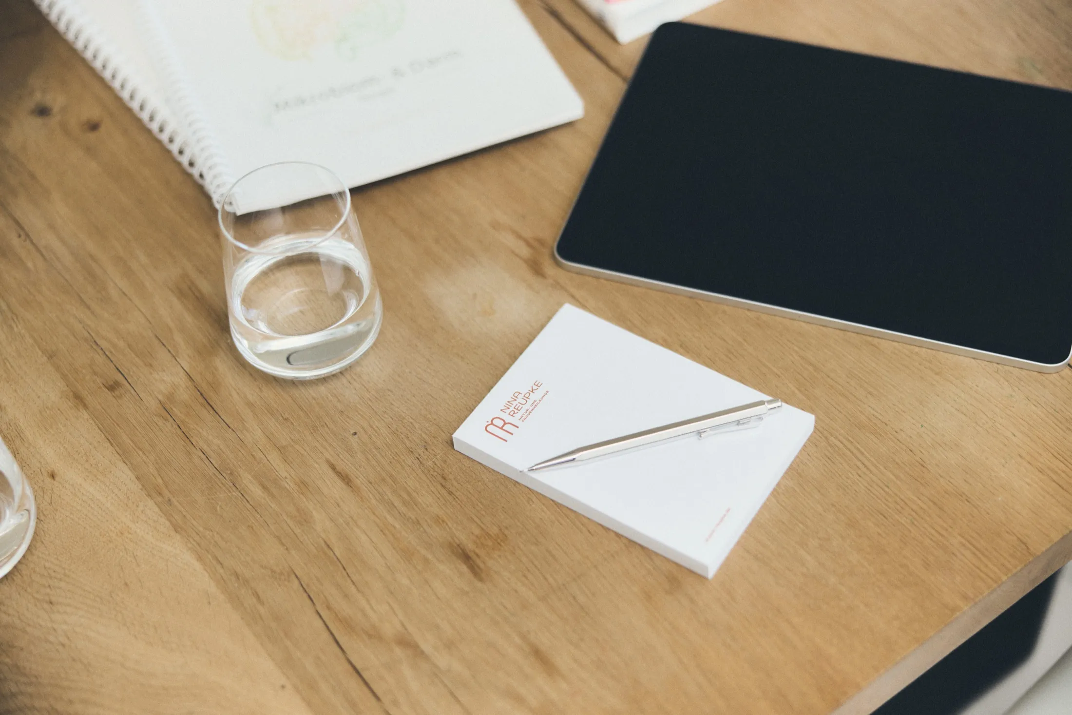 Notizblock, Stift und Tablet auf dem Beratungstisch der Praxis